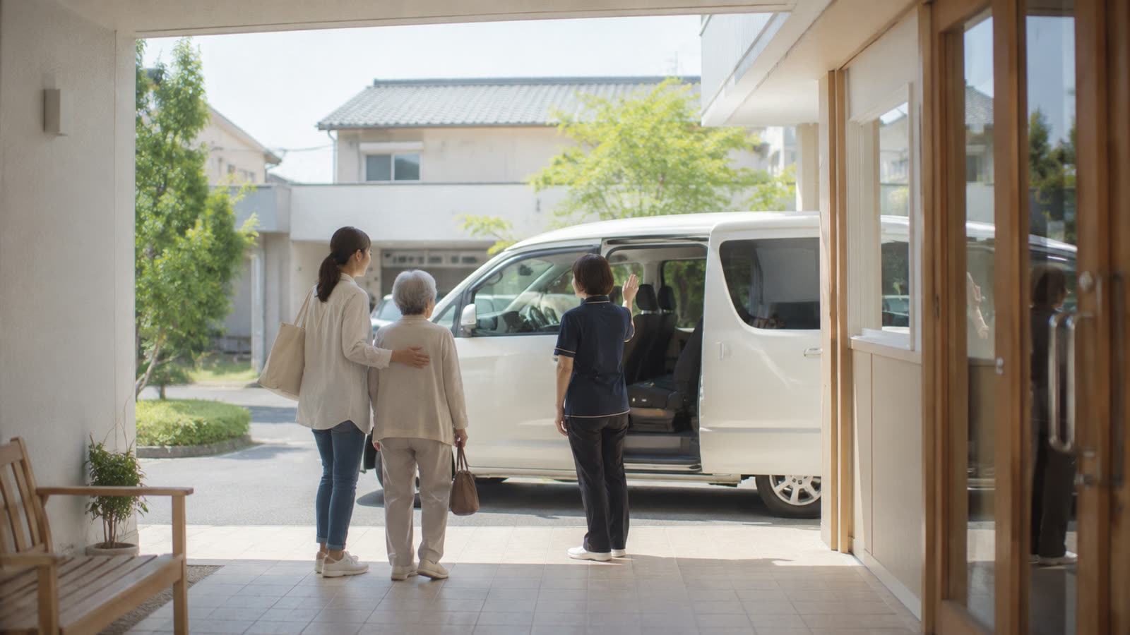 デイサービスの送迎車の前で、職員に見送られるご利用者とご家族